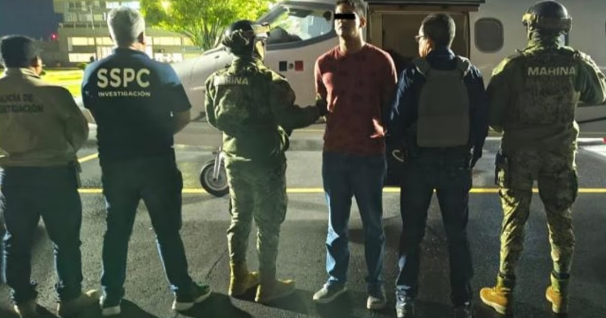 Agentes de seguridad detienen a 'El Caiser' frente a un avión durante la noche.