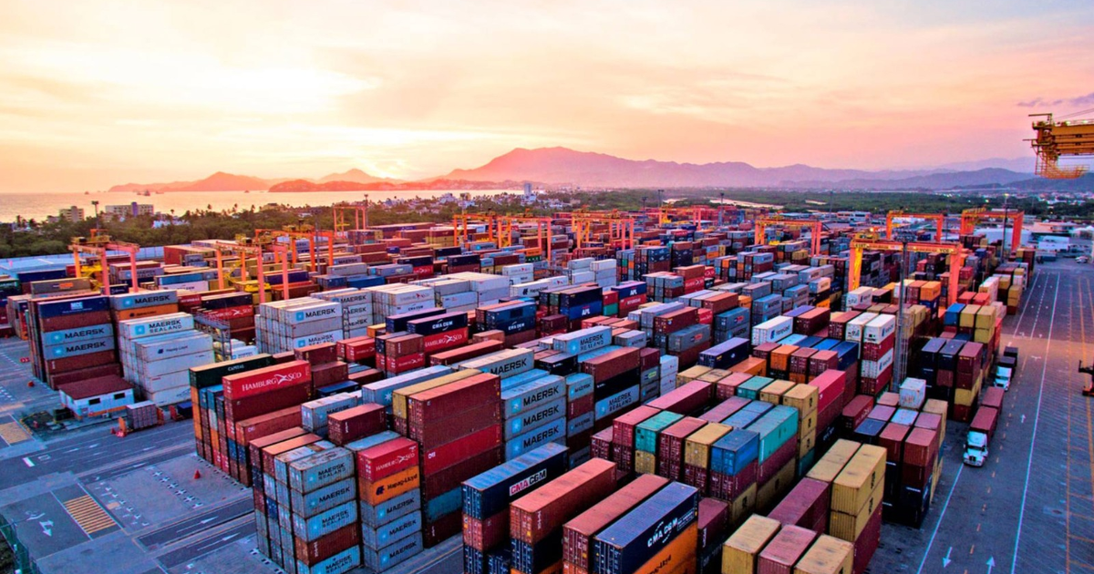 Puerto de carga con contenedores y grúas al atardecer, simbolizando el comercio internacional.