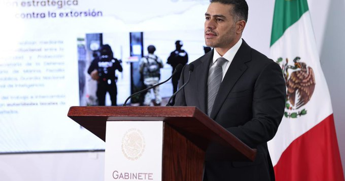 Funcionario mexicano presenta estrategia contra la extorsión desde un podio con la bandera de México al fondo.