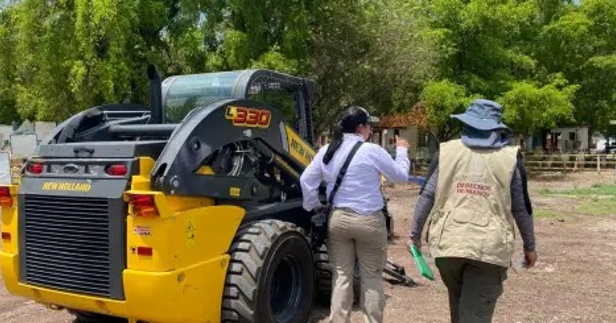 Cargador compacto New Holland con dos personas en entorno rural