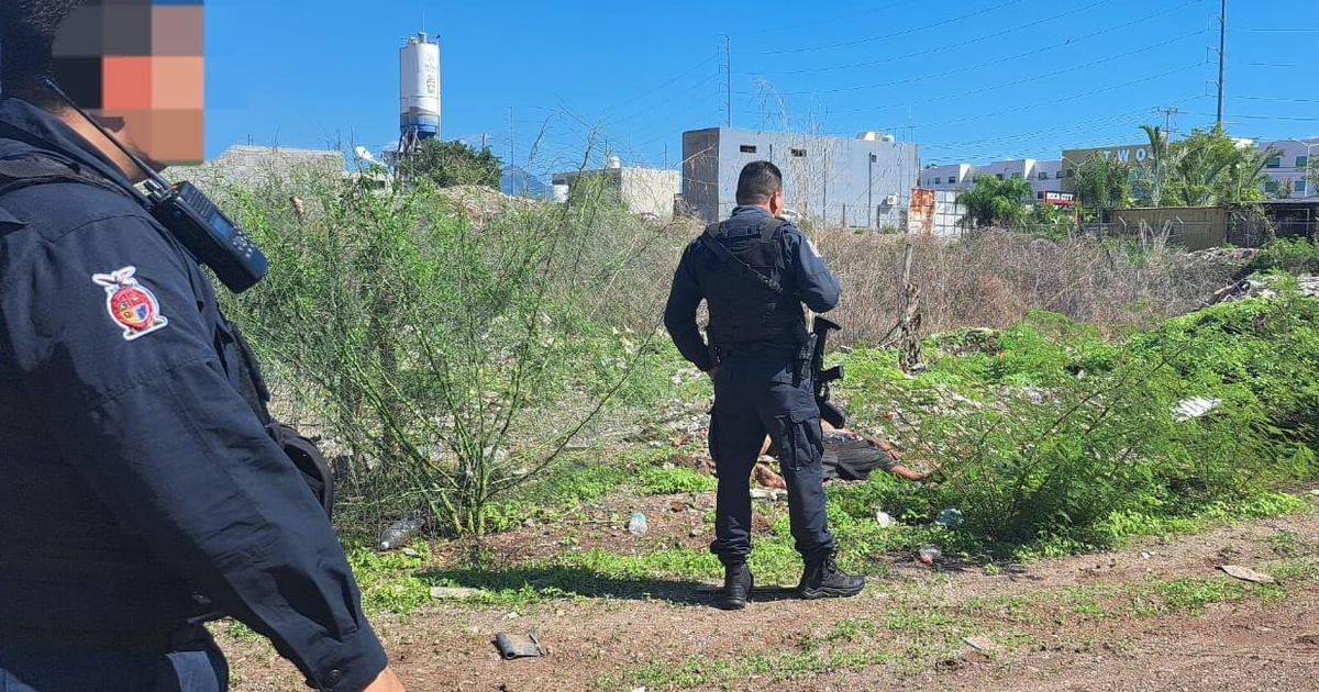 Dos miembros de las fuerzas de seguridad en Culiacán, con vegetación y edificios al fondo.
