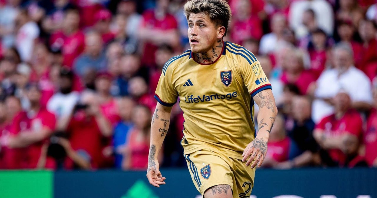 Diego Luna en el campo de juego con camiseta amarilla y detalles en azul, rodeado de aficionados.