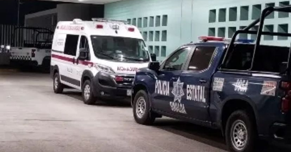 Ambulancia y camioneta de policía estatal estacionadas en área iluminada tras accidente en persecución