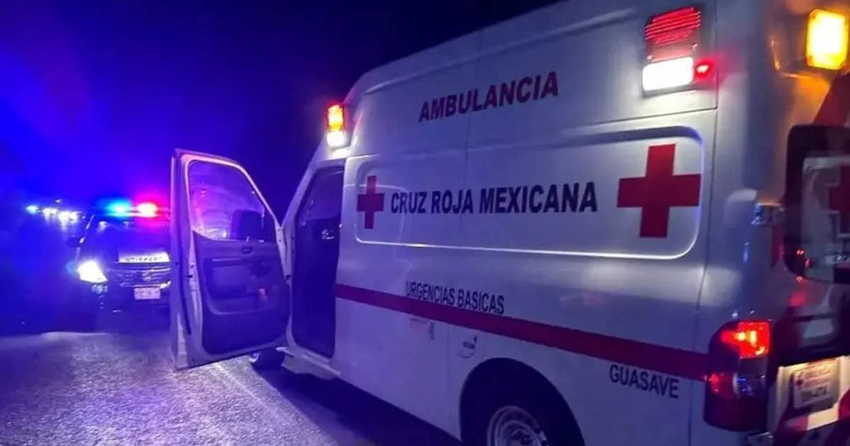 Ambulancia de la Cruz Roja Mexicana con luces de emergencia encendidas y patrulla al fondo en un entorno oscuro.