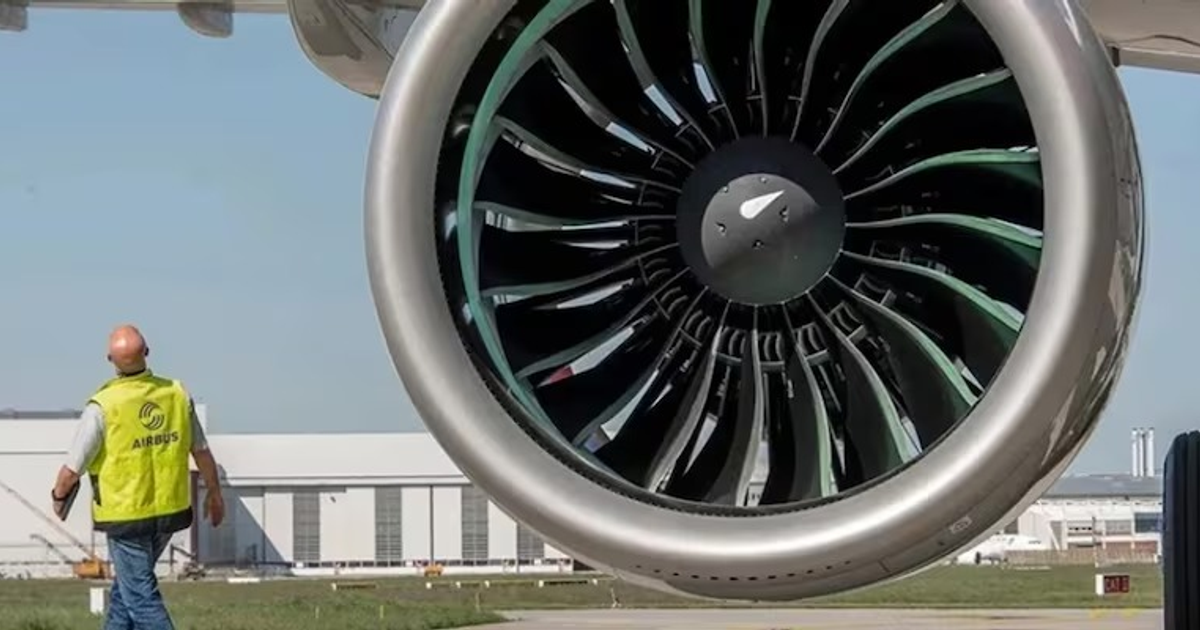 Trabajador de Airbus inspeccionando un motor de avión a reacción en una instalación industrial.