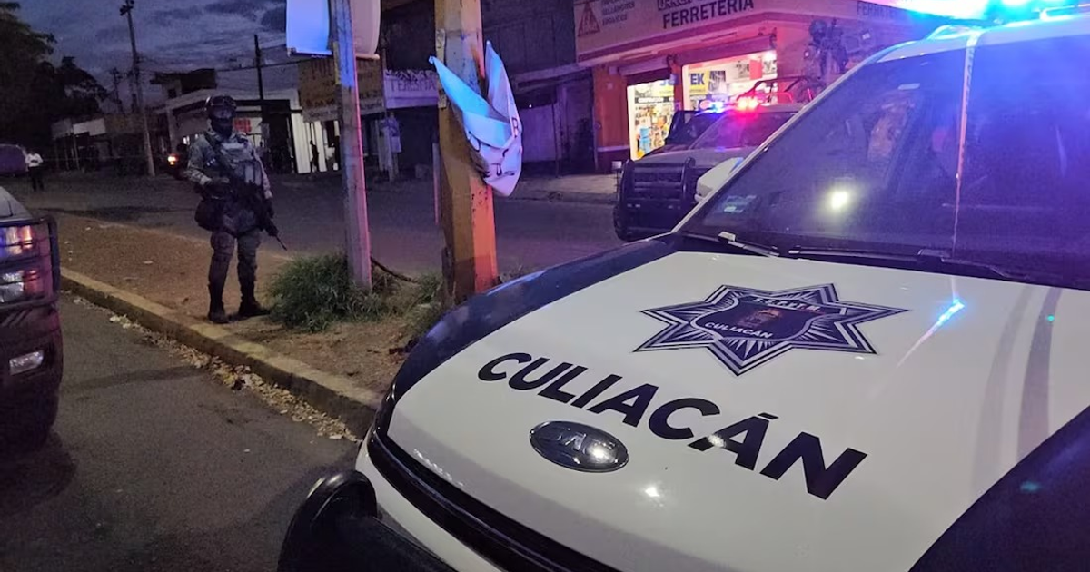 Escena nocturna con presencia policial en Culiacán, vehículo de policía y oficial armado.
