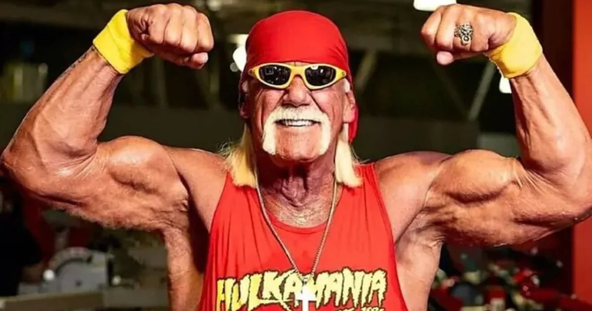 Hulk Hogan posando en un gimnasio con camiseta roja 'HULKAMANIA', bandana y gafas de sol.