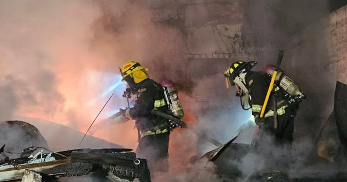 Bomberos en acción durante un incendio en Mazatlán, rodeados de humo y llamas.