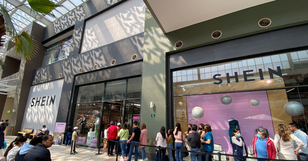 Fachada de tienda SHEIN con fila de clientes y ventanales decorados en centro comercial