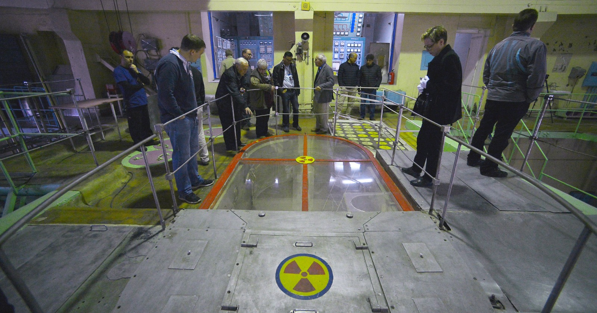 Grupo de personas en instalación nuclear con símbolo de radiación visible