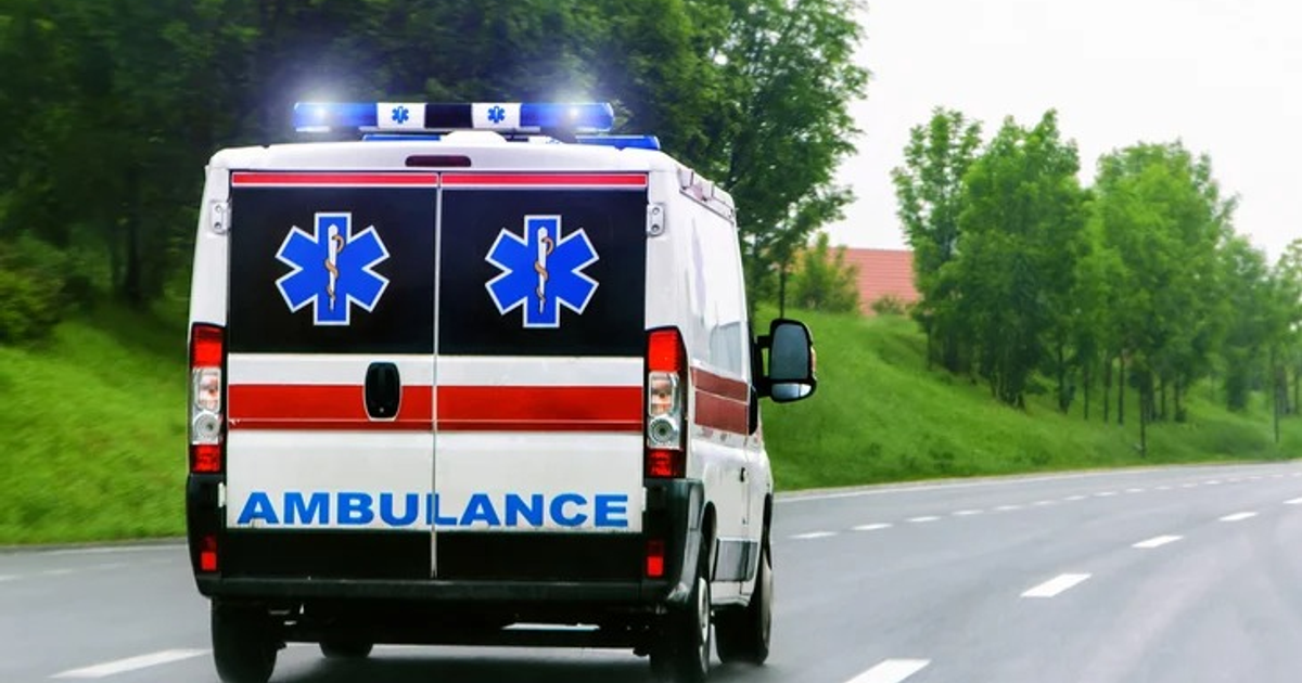 Ambulancia en carretera con luces encendidas, rodeada de árboles, simbolizando respuesta a emergencia en San Ignacio.
