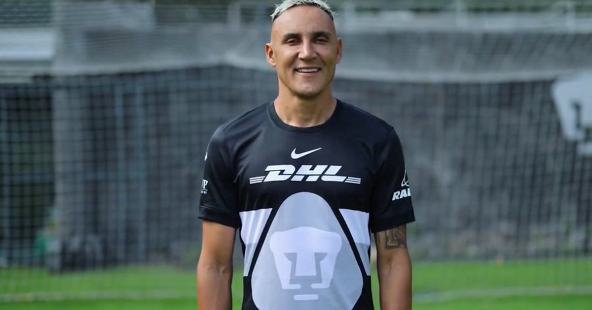 Keylor Navas sonriente en un campo de fútbol, con camiseta de DHL y Nike, tras su traspaso a Pumas.