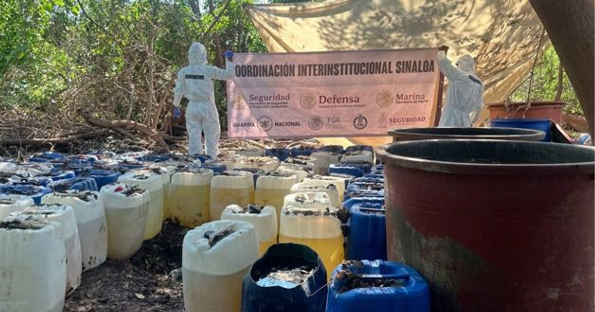 Operativo de seguridad en complejo clandestino de metanfetamina en Sinaloa con garrafones y personal en traje blanco.