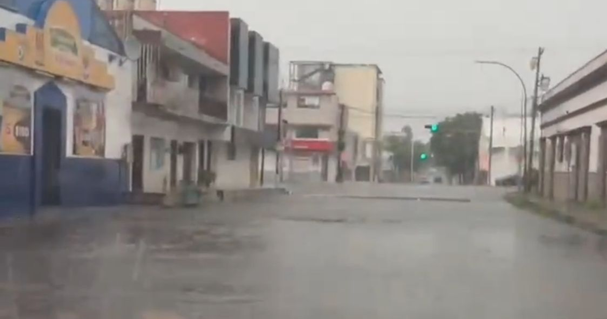 Calle inundada en Culiacán con semáforo en verde y edificios a los lados durante tormenta de julio 2025.