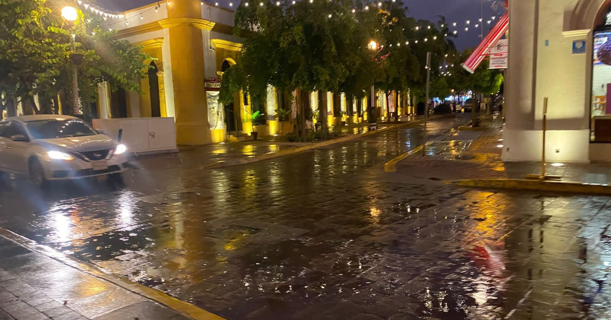 Calle nocturna en Mazatlán con pavimento mojado y luces reflejadas tras lluvias leves.