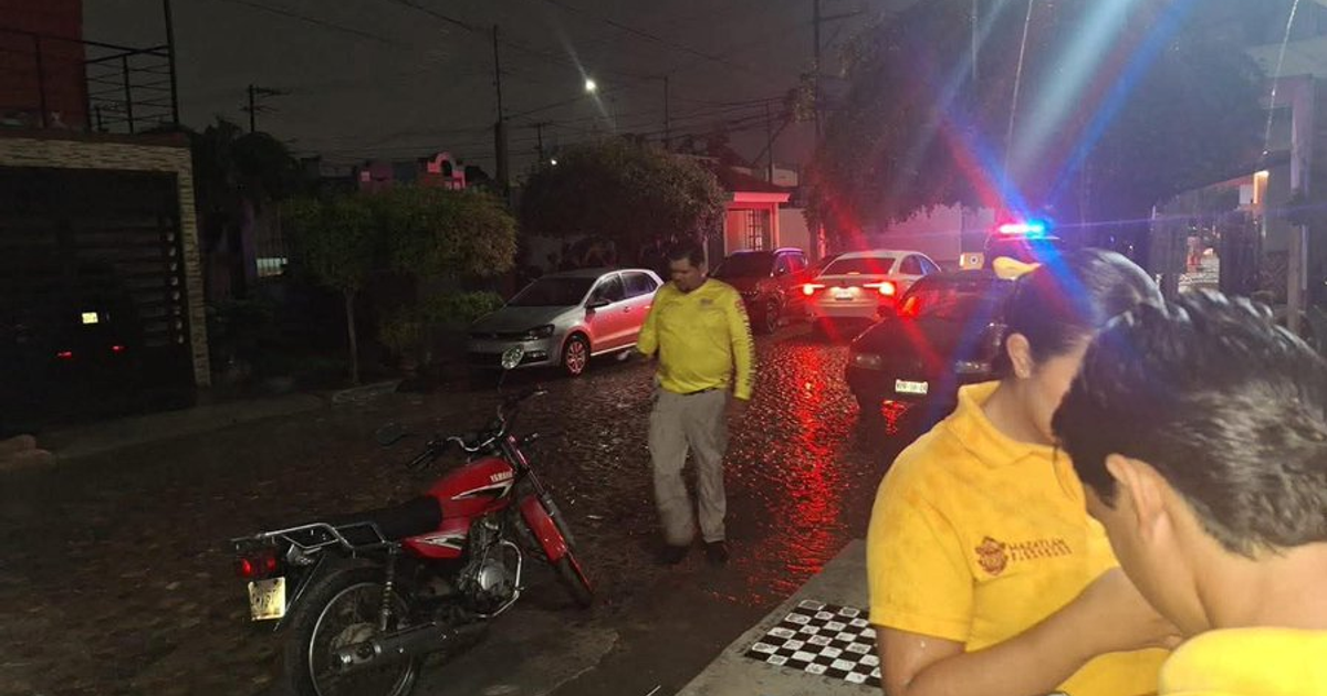 Calle nocturna en Mazatlán con vehículos estacionados y luces de emergencia