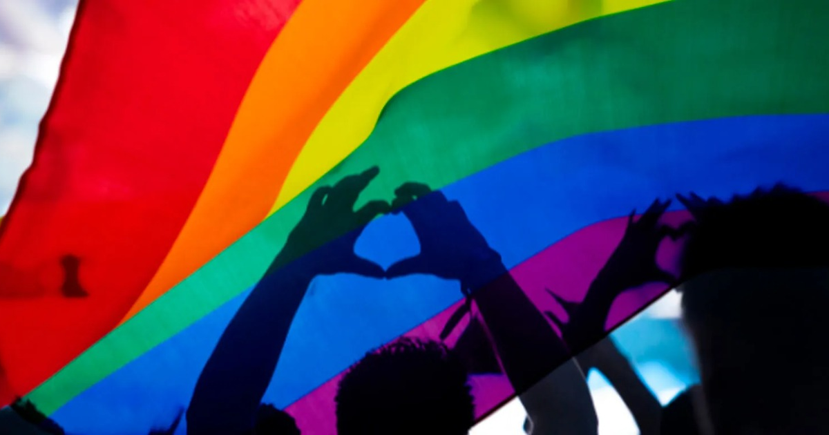Bandera del orgullo LGBTQ+ con manos en forma de corazón durante manifestación en Culiacán.