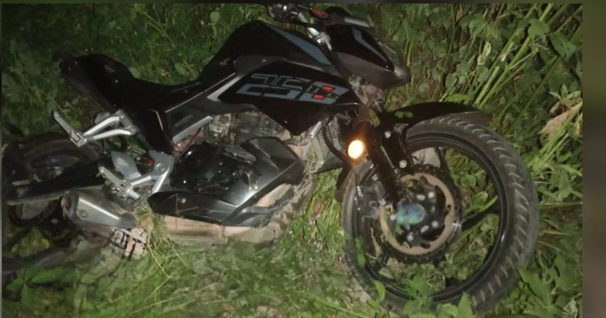 Motocicleta negra caída y cubierta de vegetación, recuperada en Mazatlán