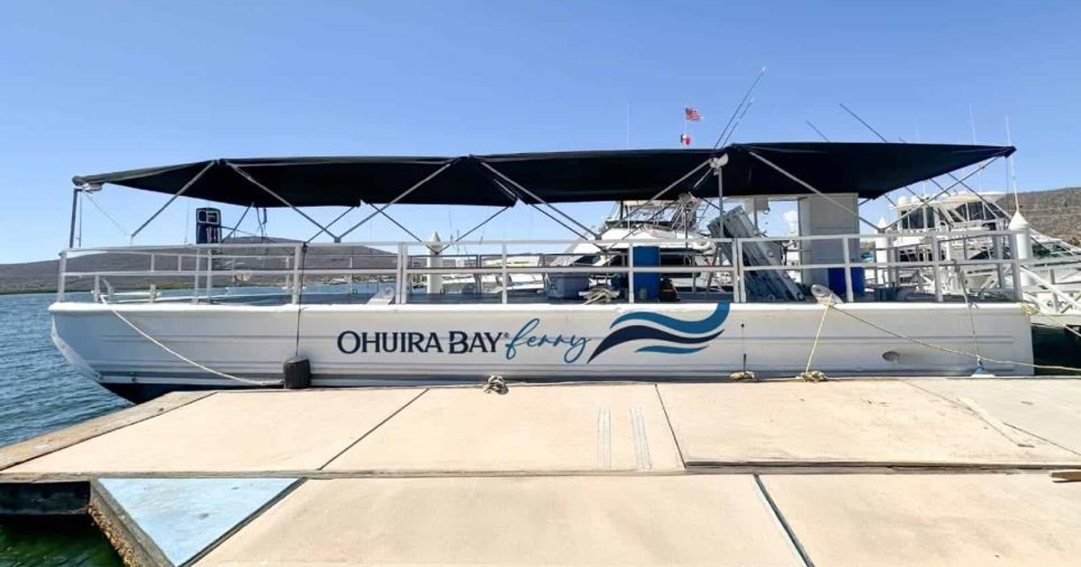 Ferry Ohuira Bay amarrado en muelle con montañas al fondo y cielo despejado.