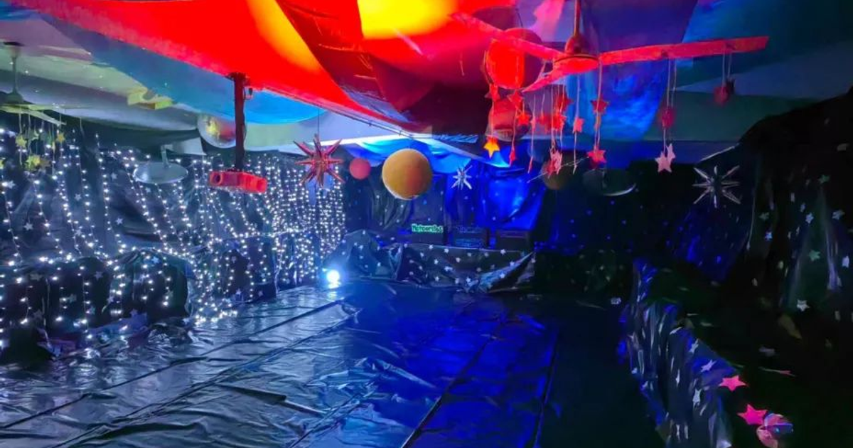 Espacio decorado con luces y planetas para evento escolar en planetario.