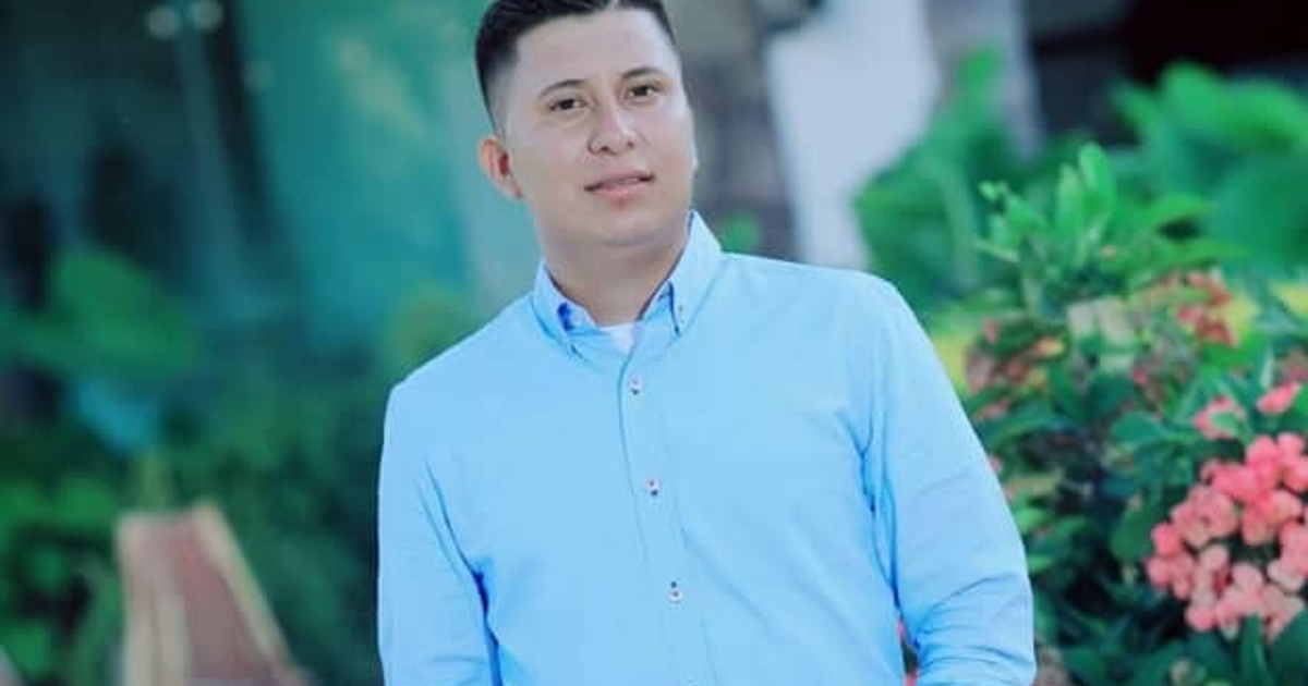 Hombre con camisa azul frente a plantas y flores