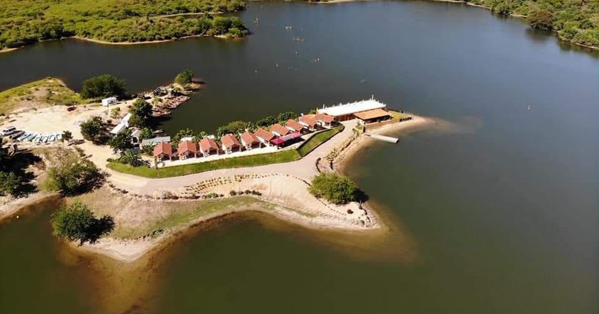 Vista aérea de la presa Picachos con cabañas y vegetación circundante