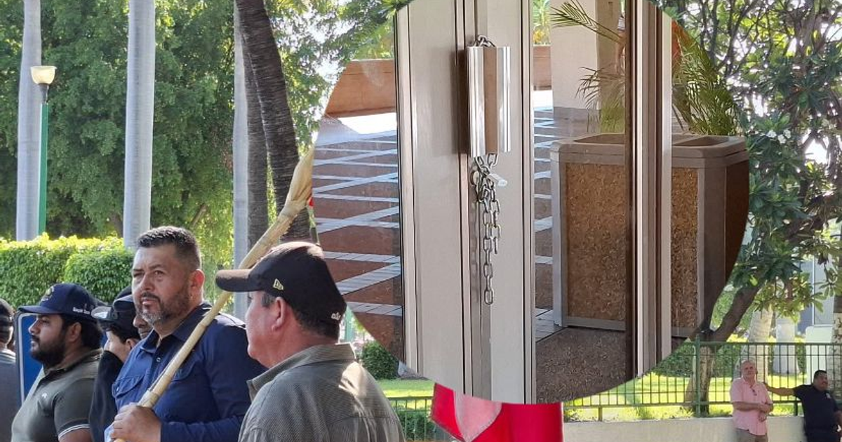 Grupo de personas en protesta por pagos atrasados del programa de maíz en Sinaloa, con detalle de área con ventanas y cadena.