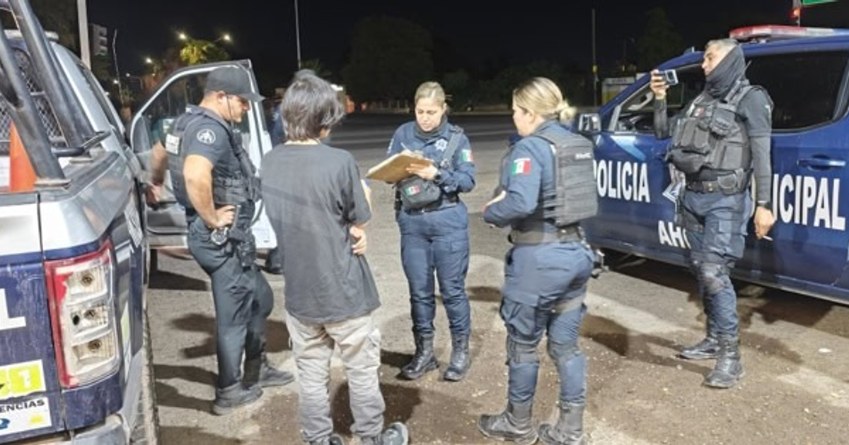 Oficiales de policía interactúan con un joven en una escena nocturna, relacionada con un rescate en la carretera Los Mochis–Topolobampo.