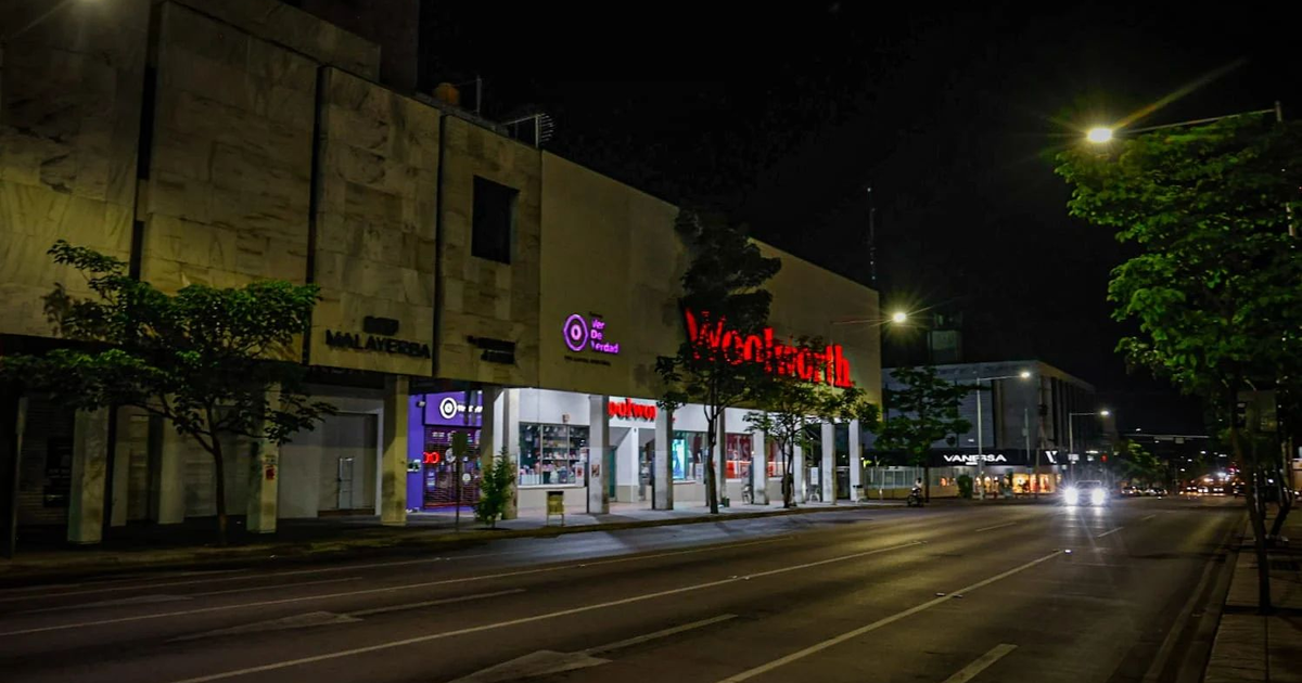 Calle nocturna en Culiacán con edificios iluminados y Woolworth destacado, tras sismo de magnitud 4.6.