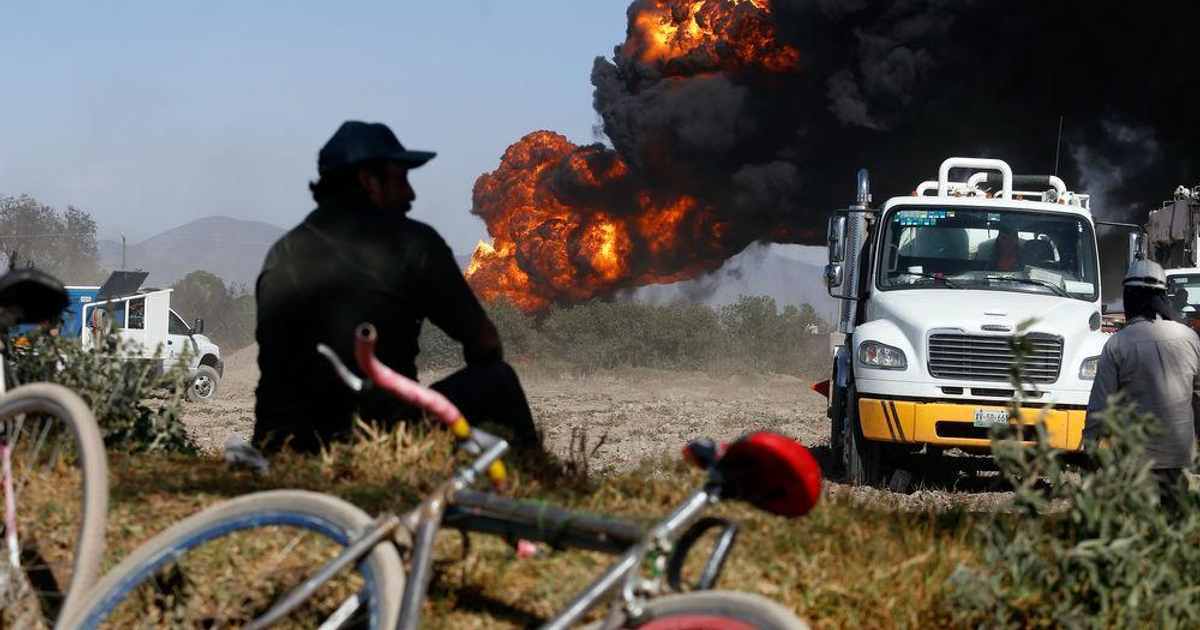 Incendio con llamas y humo negro, bicicletas en primer plano, vehículos de emergencia presentes.