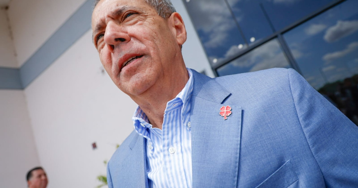 Hombre con traje azul claro y pin de trébol rojo, vinculado a proceso por irregularidades en contrato de arrendamiento.