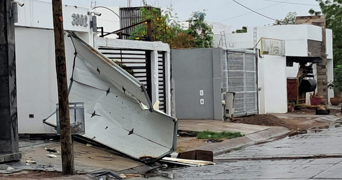 Entorno urbano dañado en Culiacán con portón caído y escombros tras ataque armado.