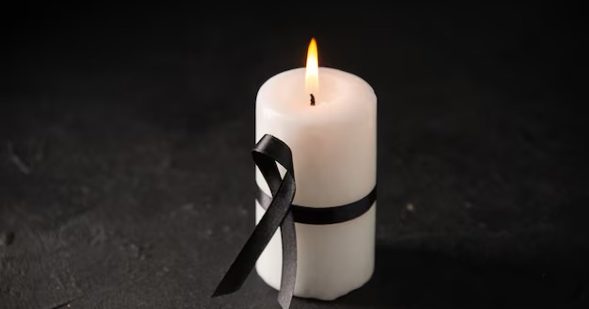 Vela blanca encendida con lazo negro en fondo oscuro