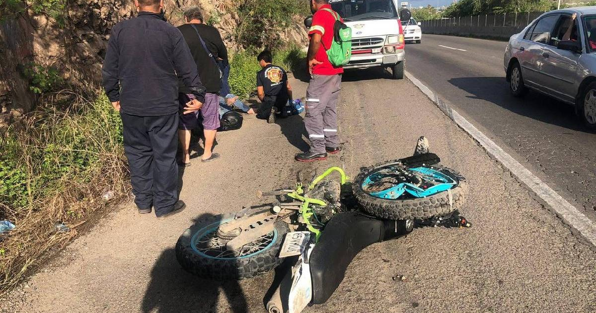 Accidente de motocicleta en carretera con personas brindando atención médica.