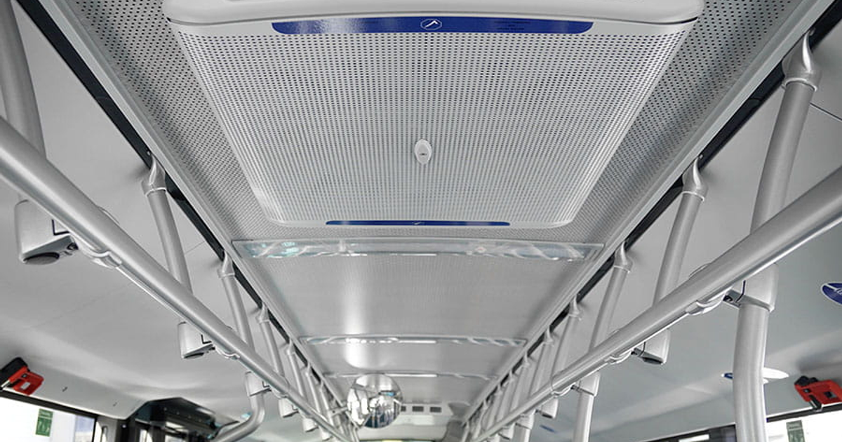 Interior de autobús urbano moderno en Mazatlán con rejillas, luces y barras metálicas.
