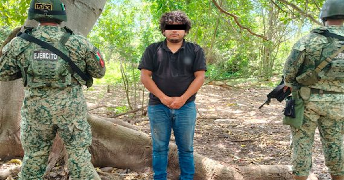 Hombre detenido junto a soldados en operativo en Elota, Sinaloa, con fondo de bosque.