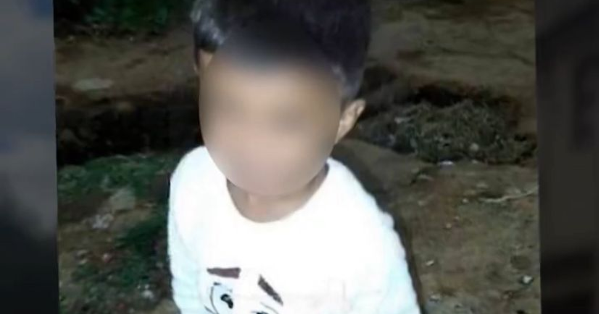 Niño de pie en exterior con camiseta blanca, rostro difuminado