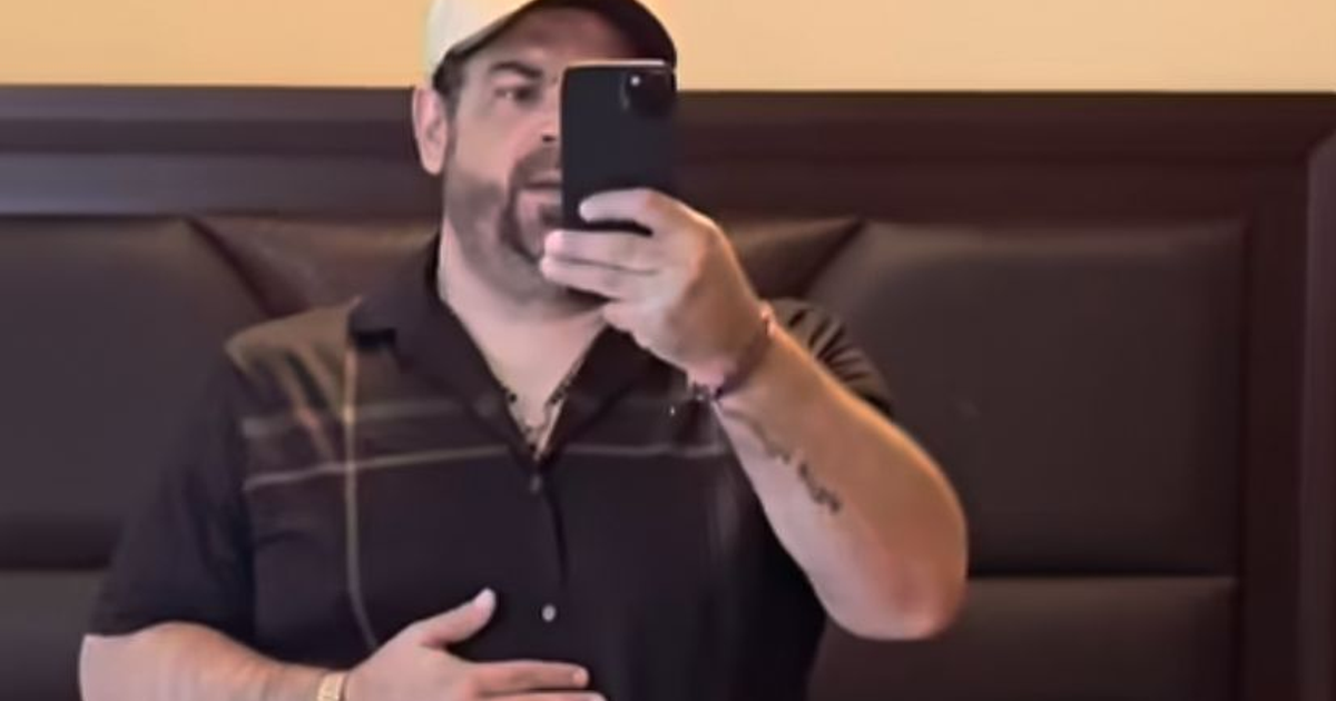 Camilo Ochoa Delgado tomando una selfie en un espejo, vestido con camiseta negra y gorra.