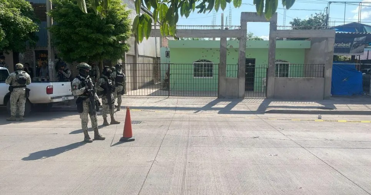 Agentes de seguridad en Culiacán tras ataque armado, con casa verde al fondo.