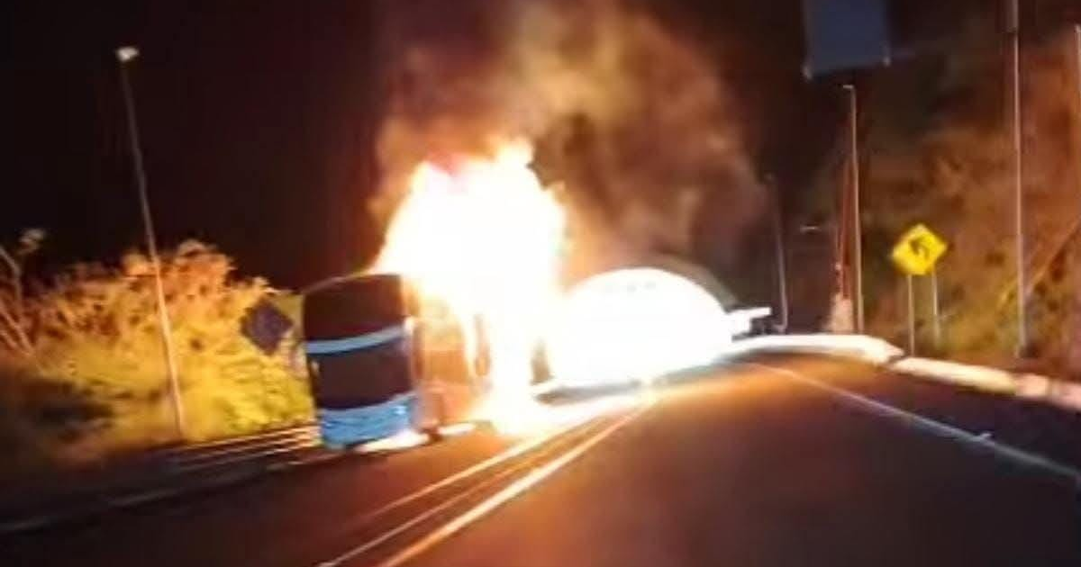 Autobús en llamas en la autopista Mazatlán-Durango durante la noche, con humo y señales de tráfico visibles.
