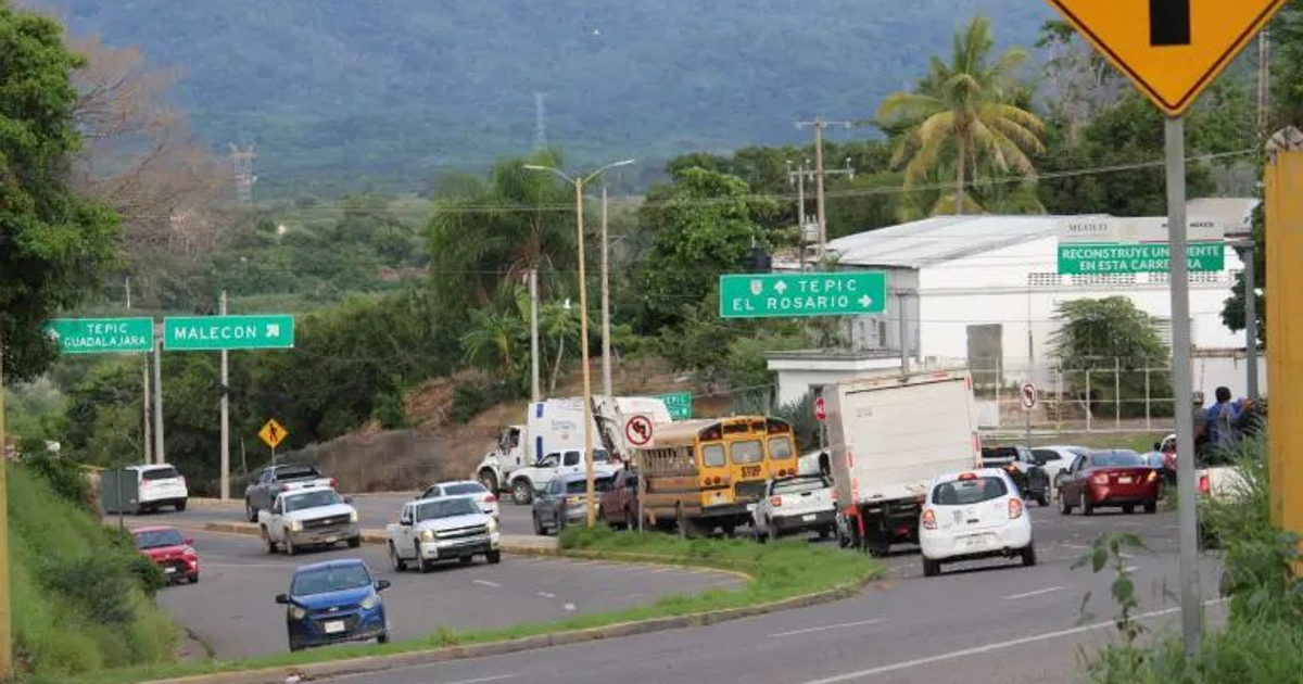 Carretera México 15 con tráfico moderado, autobús amarillo y paisaje montañoso al fondo.