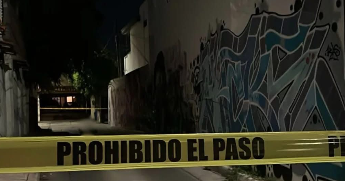 Callejón nocturno con cinta de advertencia y murales, relacionado con un hallazgo de cadáver en Culiacán.