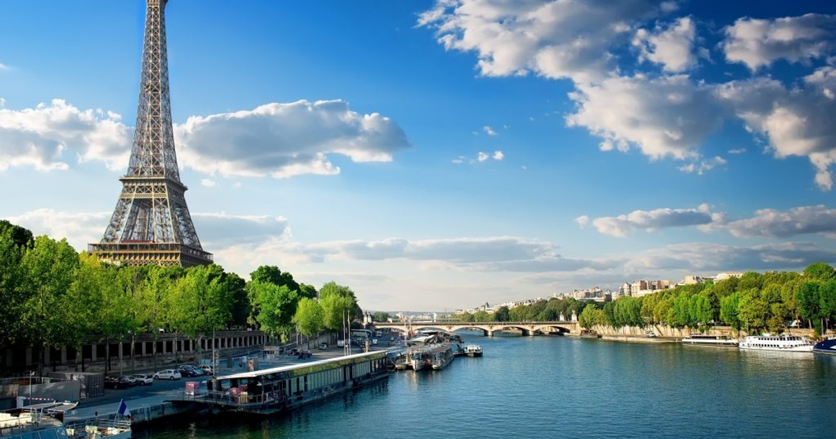 Torre Eiffel y Río Sena en París con cielo despejado y barcos navegando