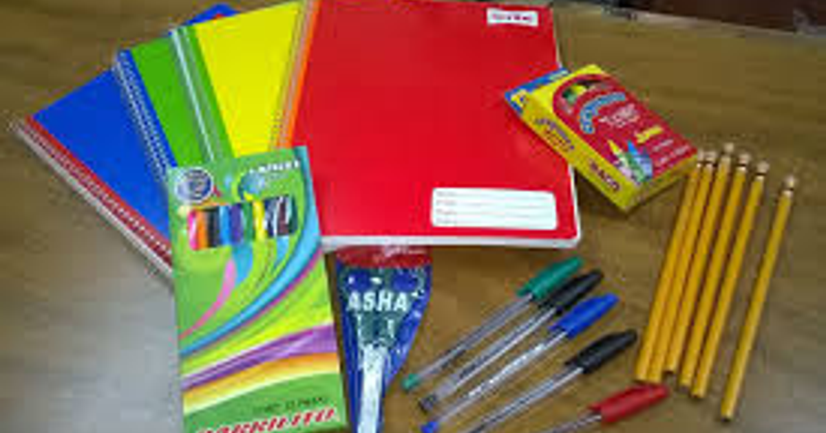 Útiles escolares sobre mesa de madera: cuadernos, bolígrafos, lápices y ceras.