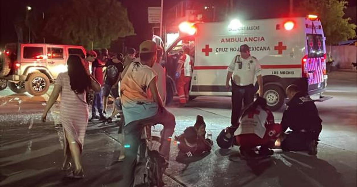 Ambulancia de la Cruz Roja Mexicana en escena de accidente nocturno con luces de emergencia encendidas.