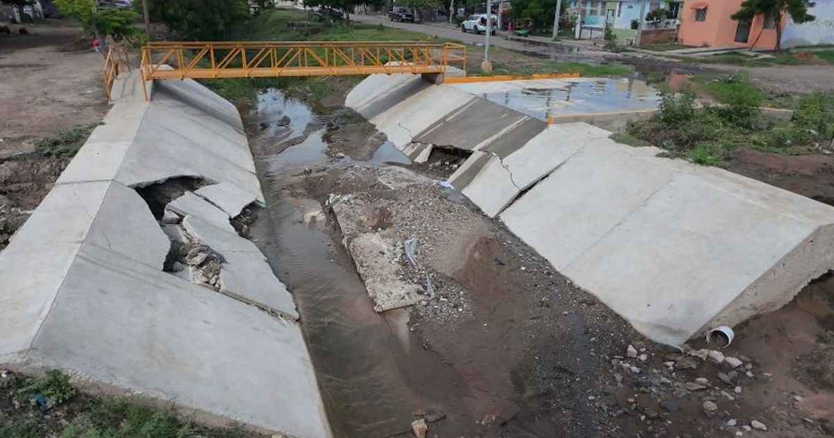 Canal de concreto dañado con puente amarillo en Mazatlán
