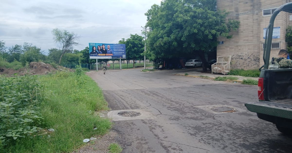Calle en Culiacán con vehículo, militar y cartel publicitario