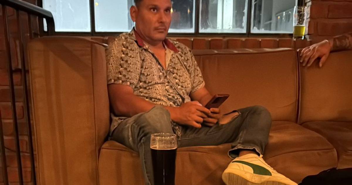 Persona sentada en un sofá con un teléfono móvil y un vaso de cerveza en un café, simbolizando la depresión y la salud mental.