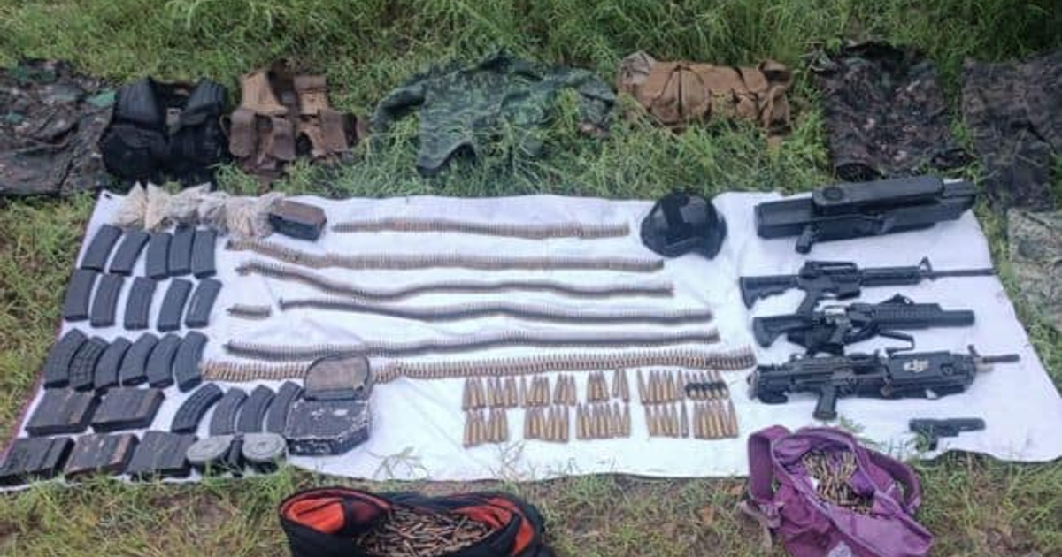 Arsenal decomisado en San Ignacio con armas largas, municiones y equipo táctico sobre tela en área con hierba.