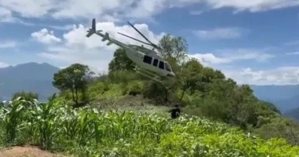 Helicóptero de Protección Civil sobrevuela paisaje verde en Otáez, Durango, durante búsqueda de joven desaparecido.